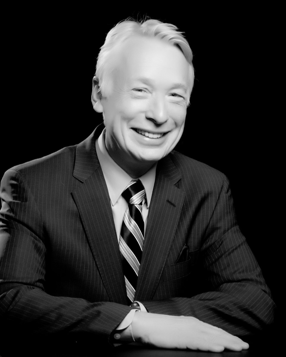 Dr. Glenn Thomas, smiling, in a dark pinstriped suit
