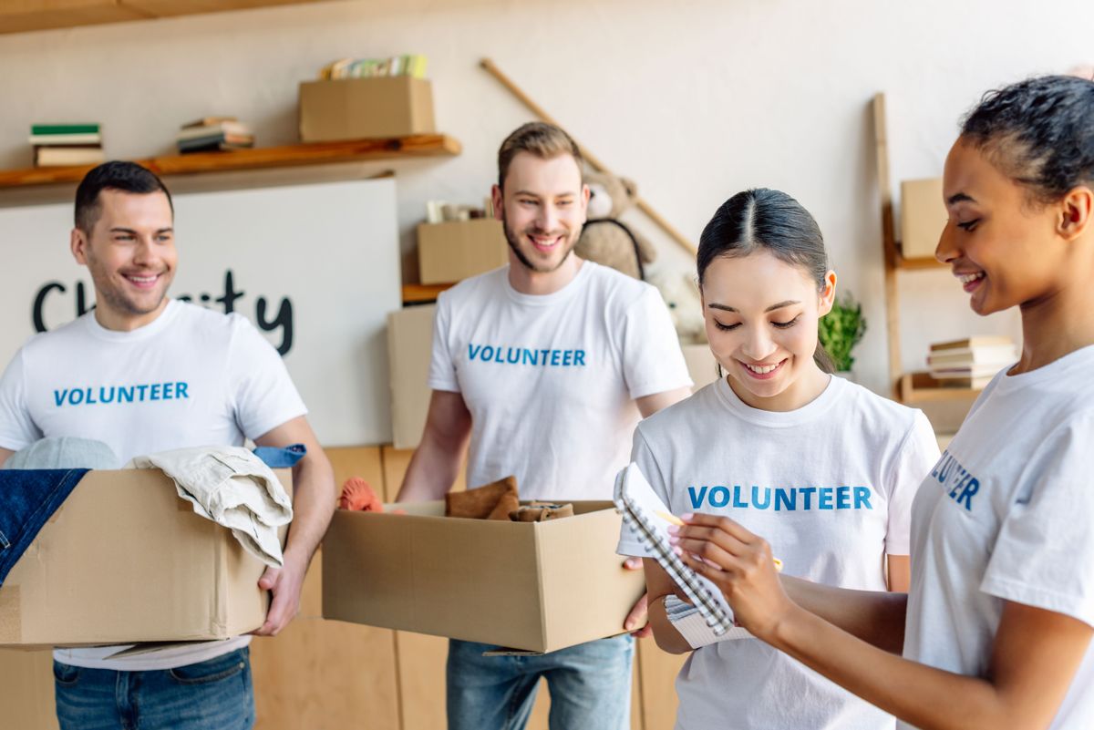 Four volunteers laughing together as they pack donation boxes